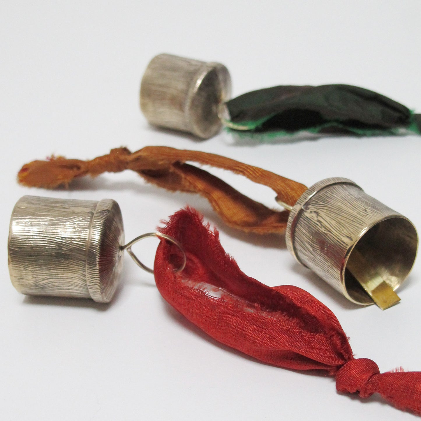 Brass bells with red fabric and orange string on a white background